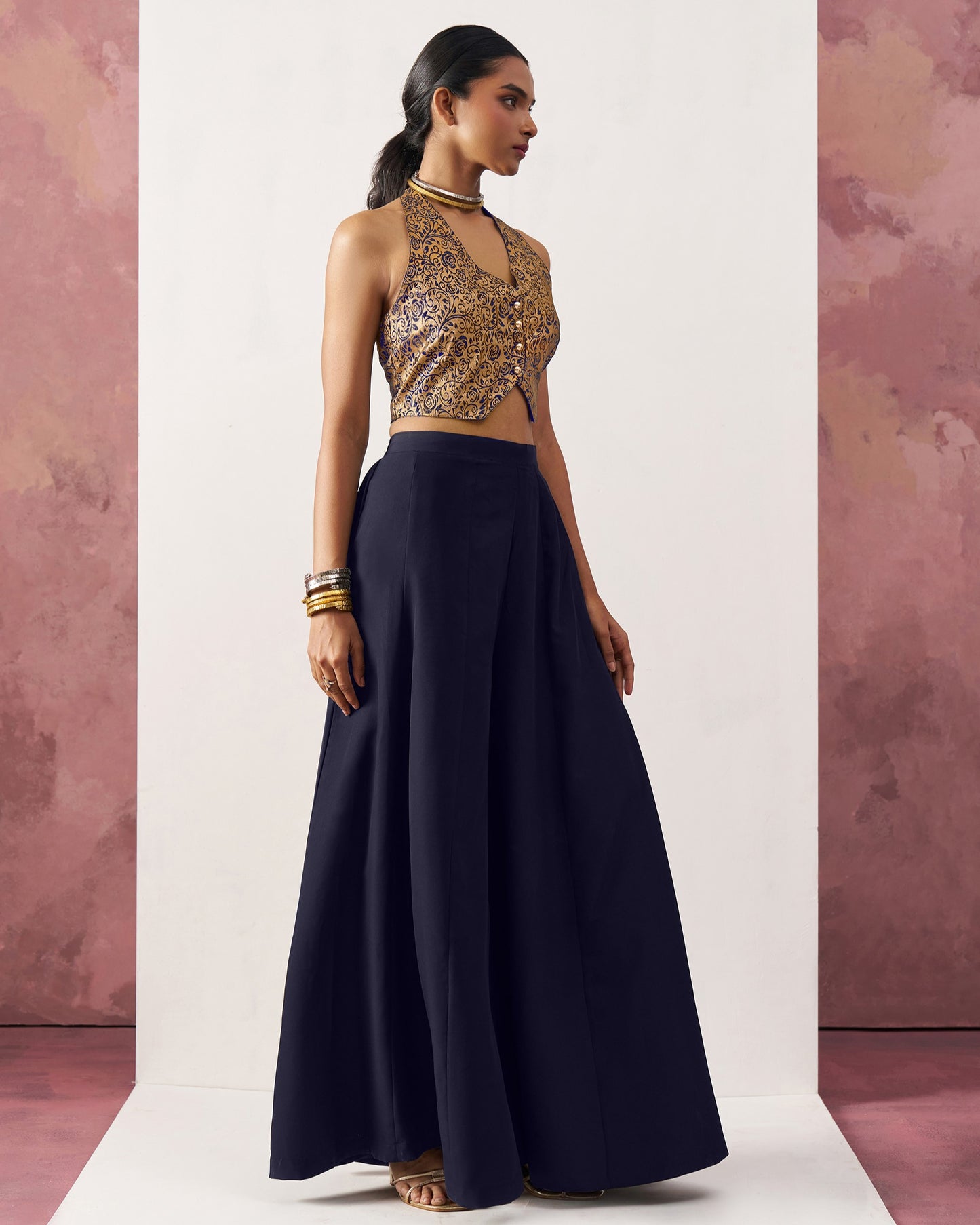 Woman wearing a gold sequin top and navy skirt against a pink and white background