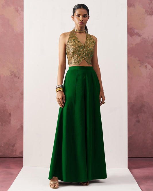 Woman wearing a gold sequin top and green skirt against a pink and white background