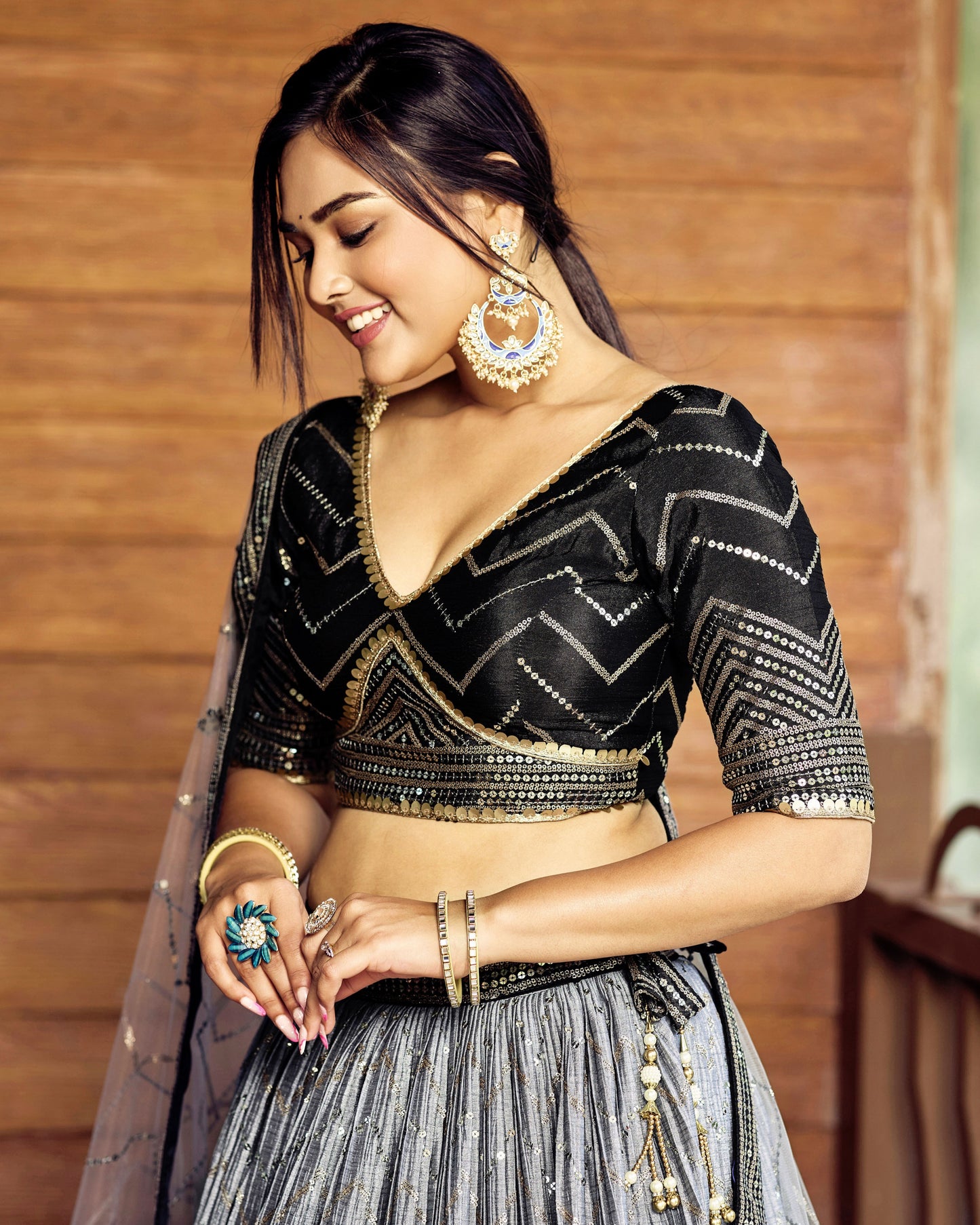 Woman wearing a black and gold traditional outfit with jewelry against a wooden background