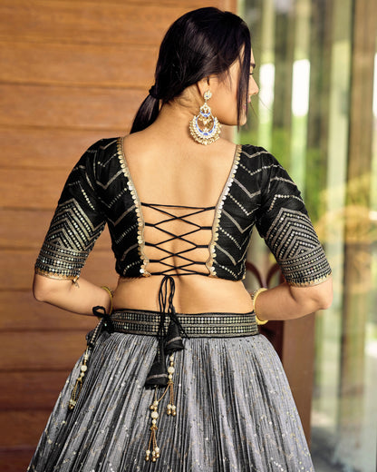 Woman wearing a traditional outfit with intricate designs, standing against a blurred background.