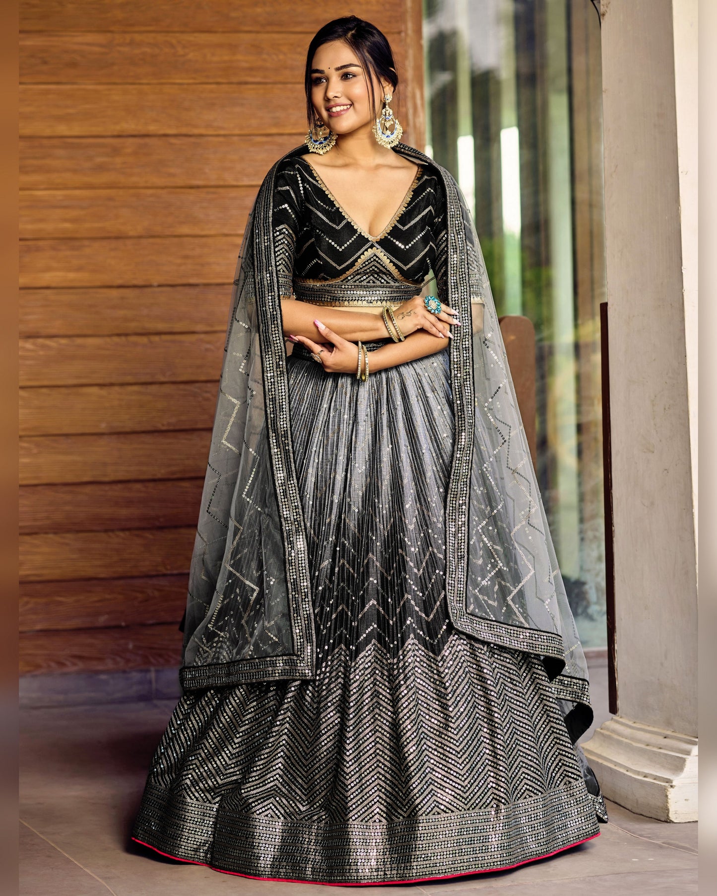 Woman wearing a black and gray traditional outfit with a wooden wall background