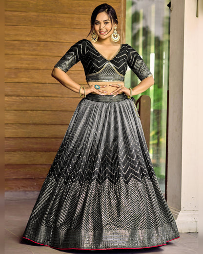 Woman wearing a black and gray patterned traditional outfit indoors.