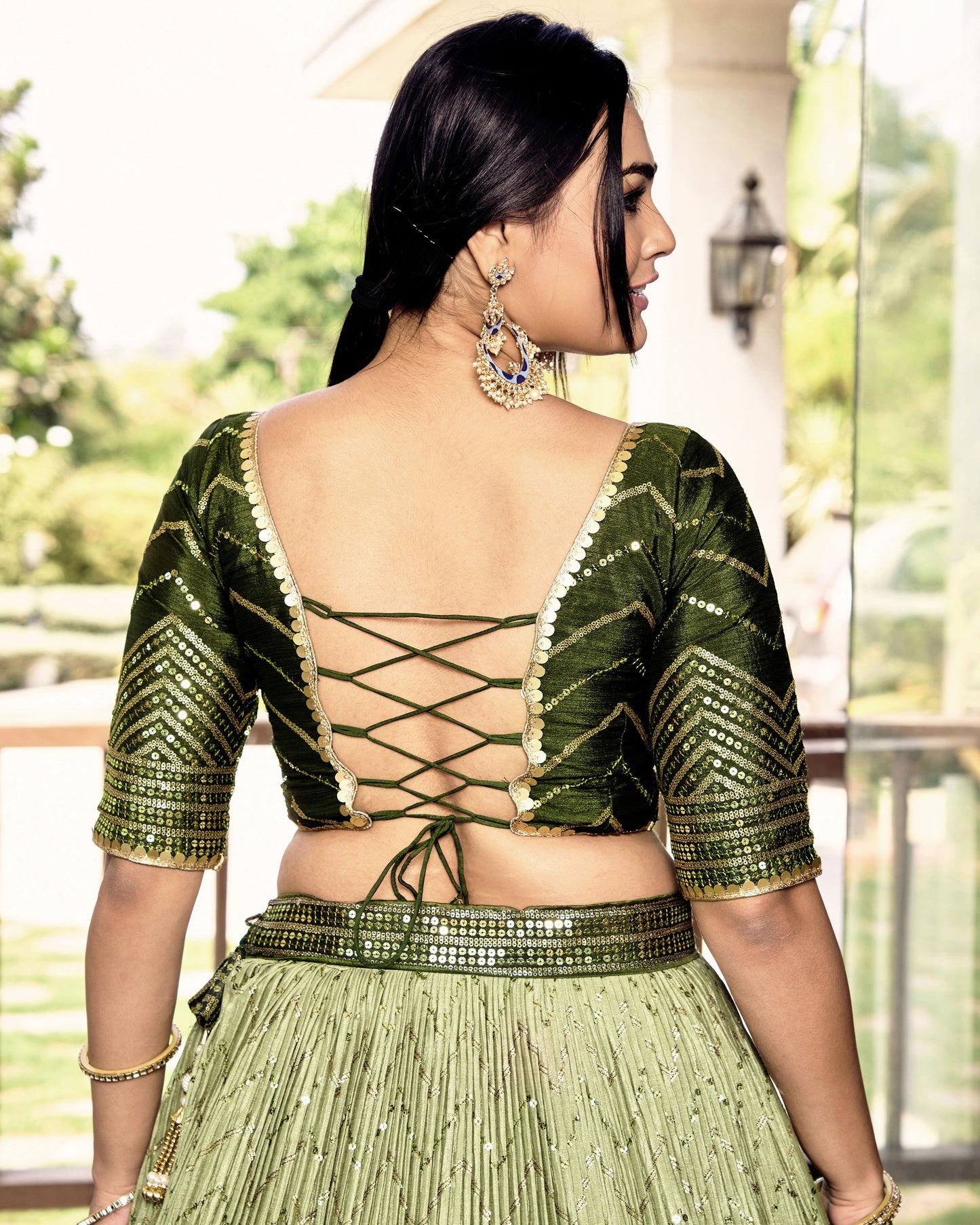 Woman wearing a green traditional outfit with intricate designs.