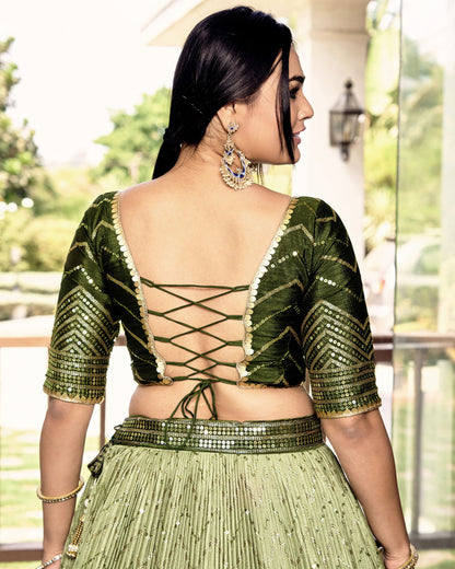 Woman wearing a green traditional outfit with intricate designs.