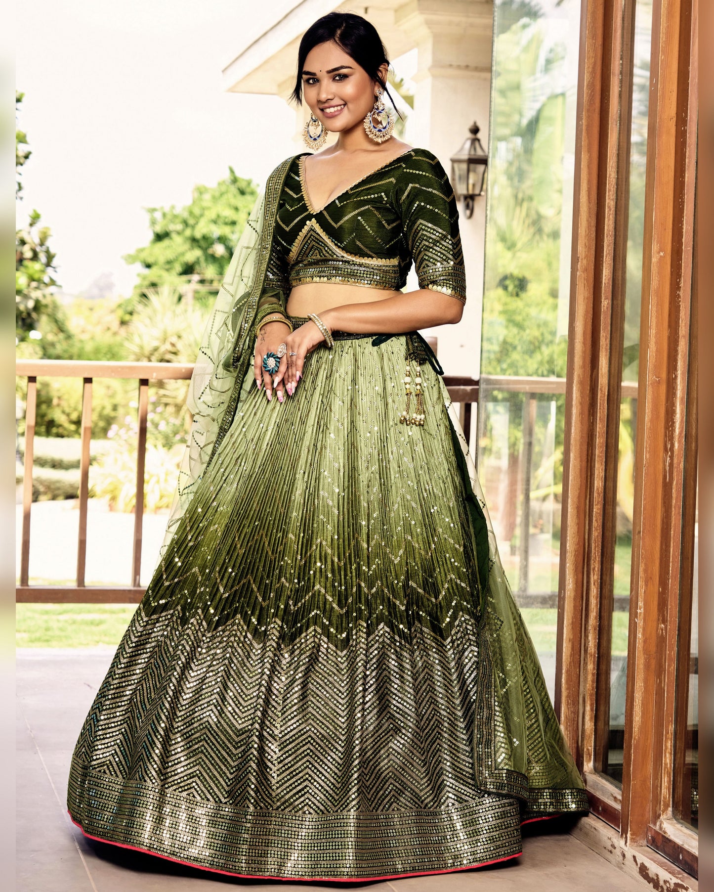 Woman in a green and black traditional outfit standing on a balcony.