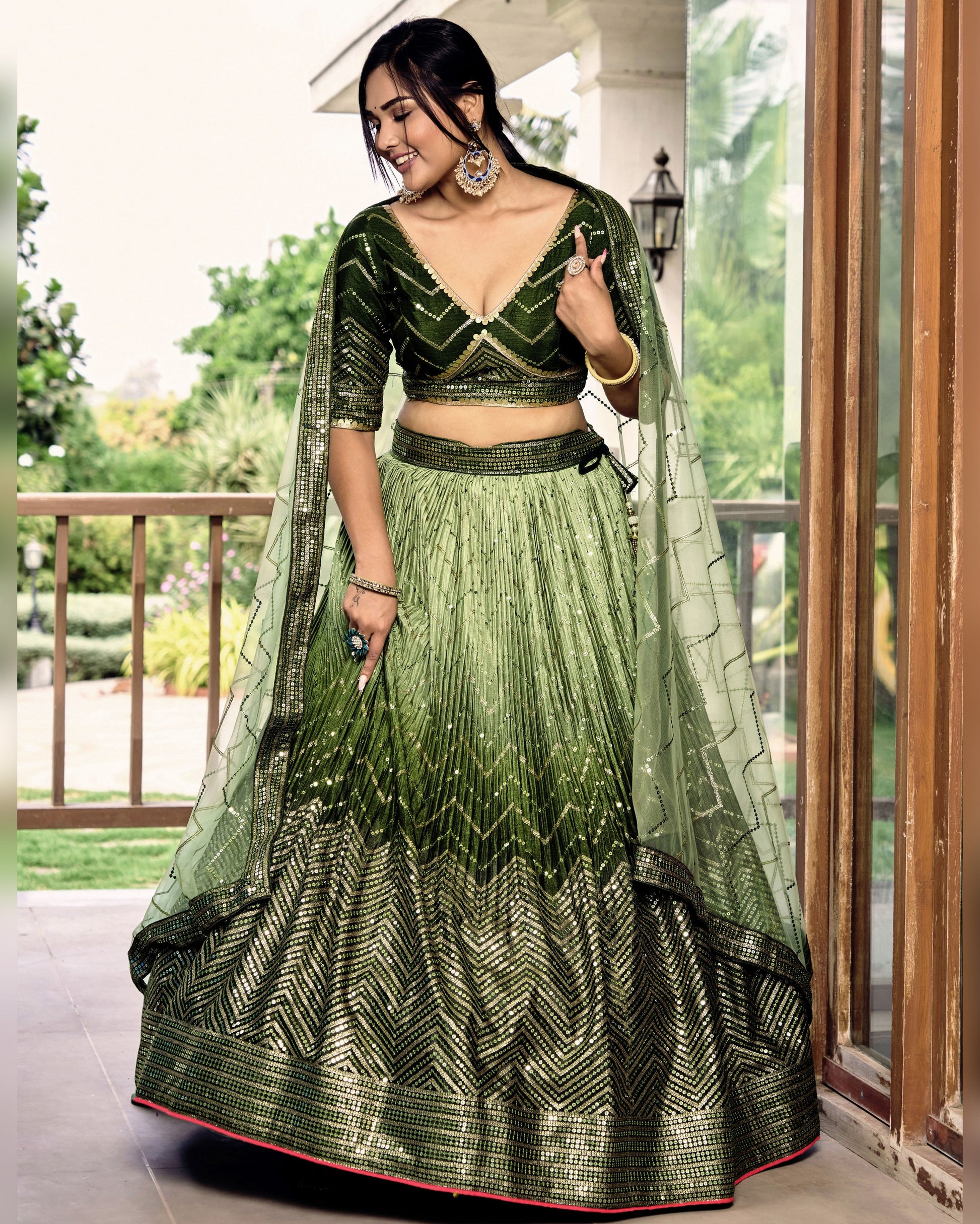 Woman in a green and black traditional outfit standing outdoors.