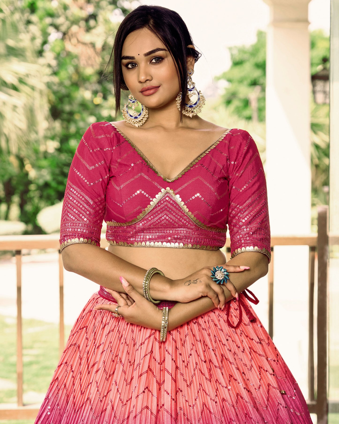 Woman wearing a pink traditional outfit with jewelry in an outdoor setting