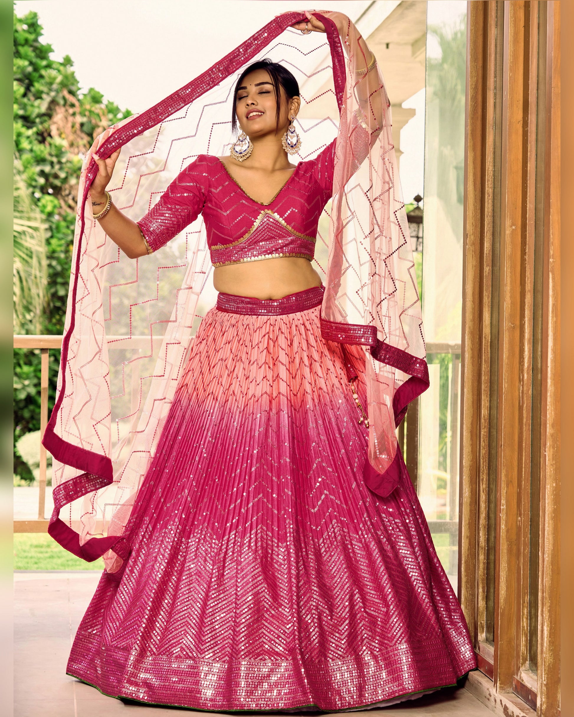 Woman wearing a pink and red traditional outfit with a matching dupatta.