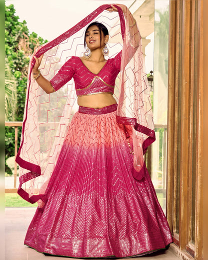 Woman wearing a pink and red traditional outfit with a matching dupatta.