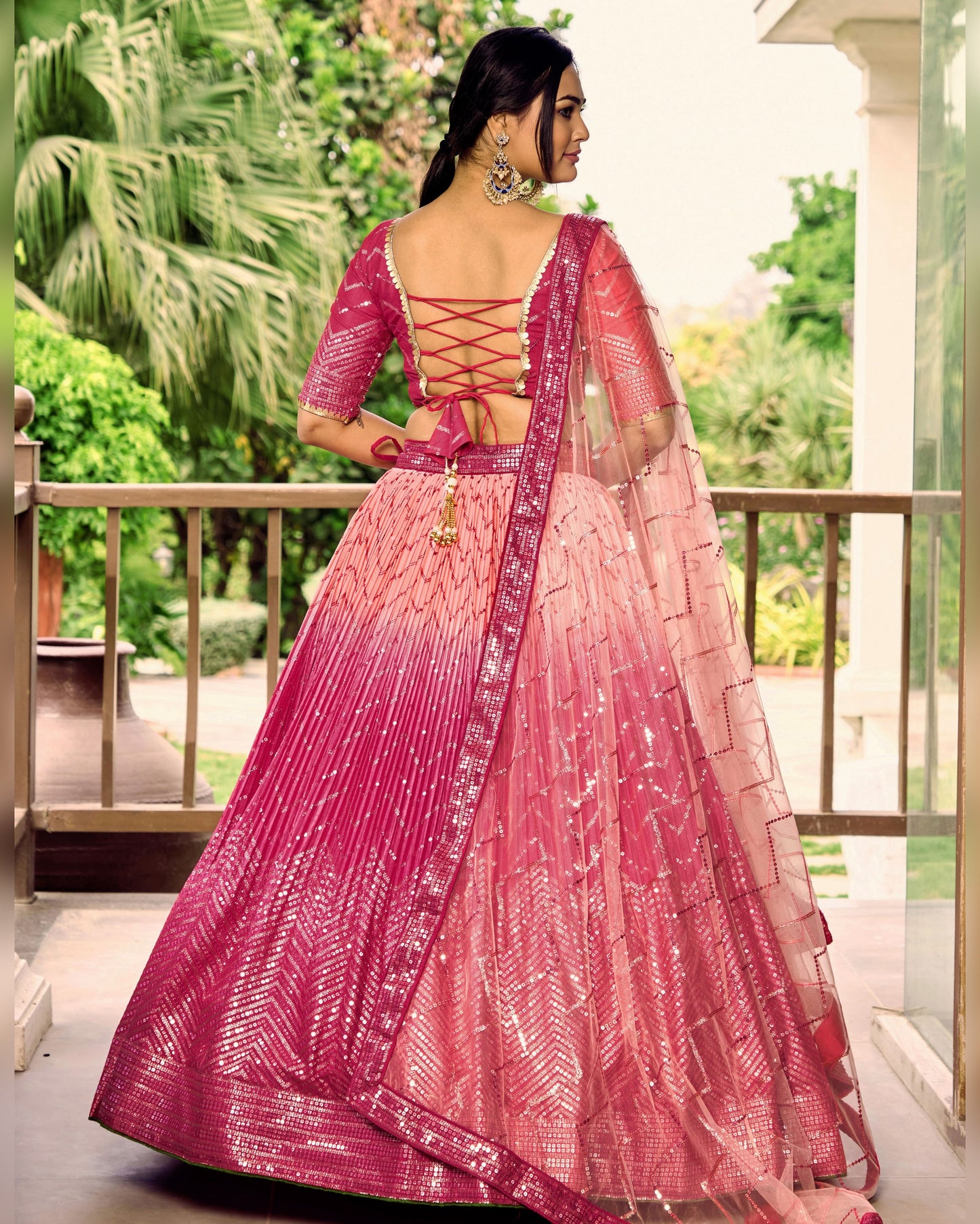 Woman wearing a pink and purple traditional outfit with a blurred green outdoor background