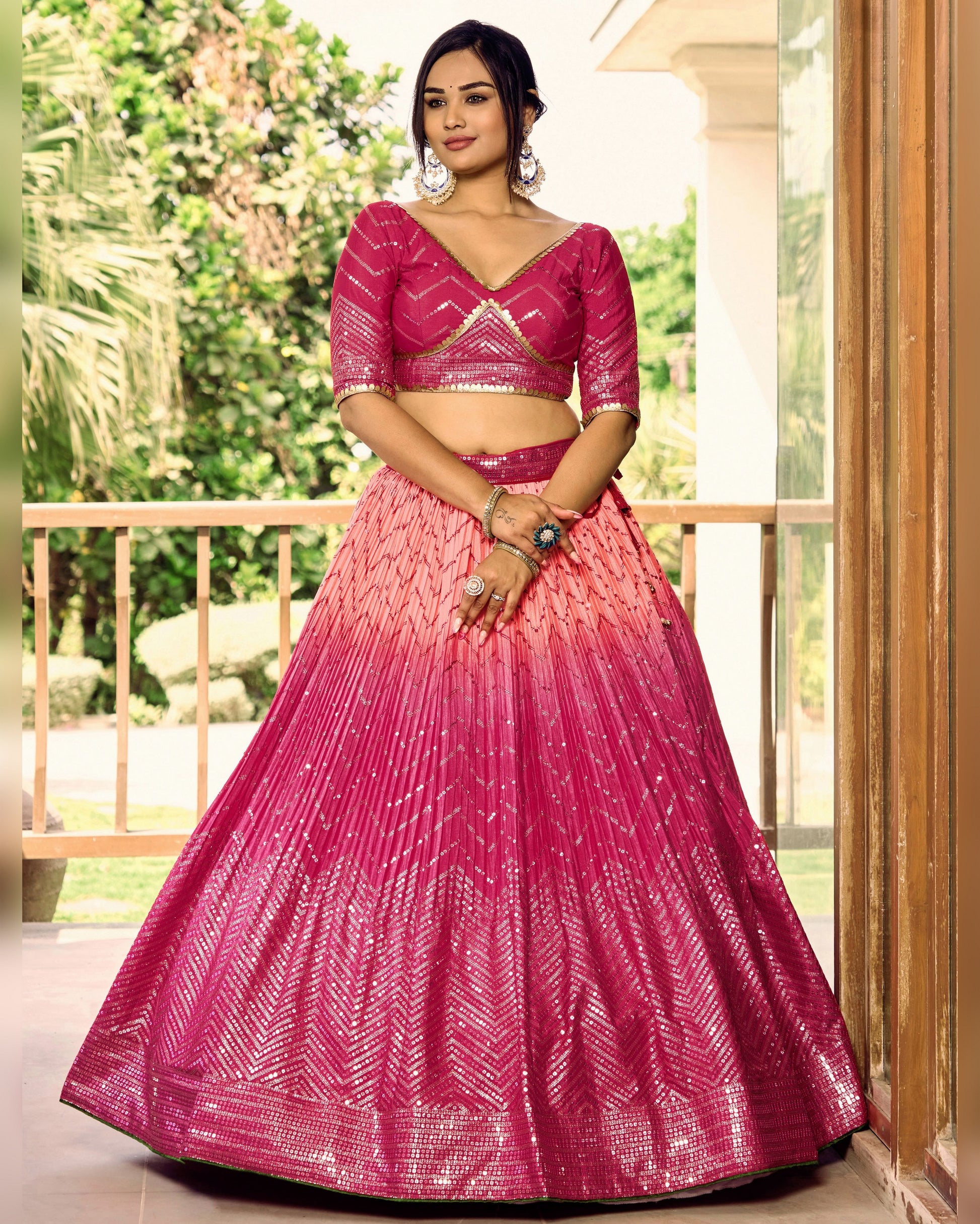 Woman wearing a pink and red lehenga with a blurred outdoor background