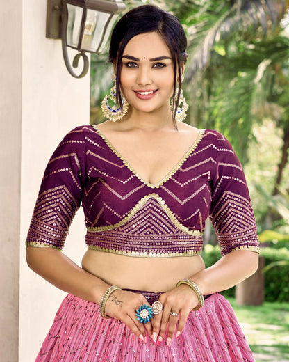 Woman wearing a purple and pink traditional outfit with a blurred green outdoor background