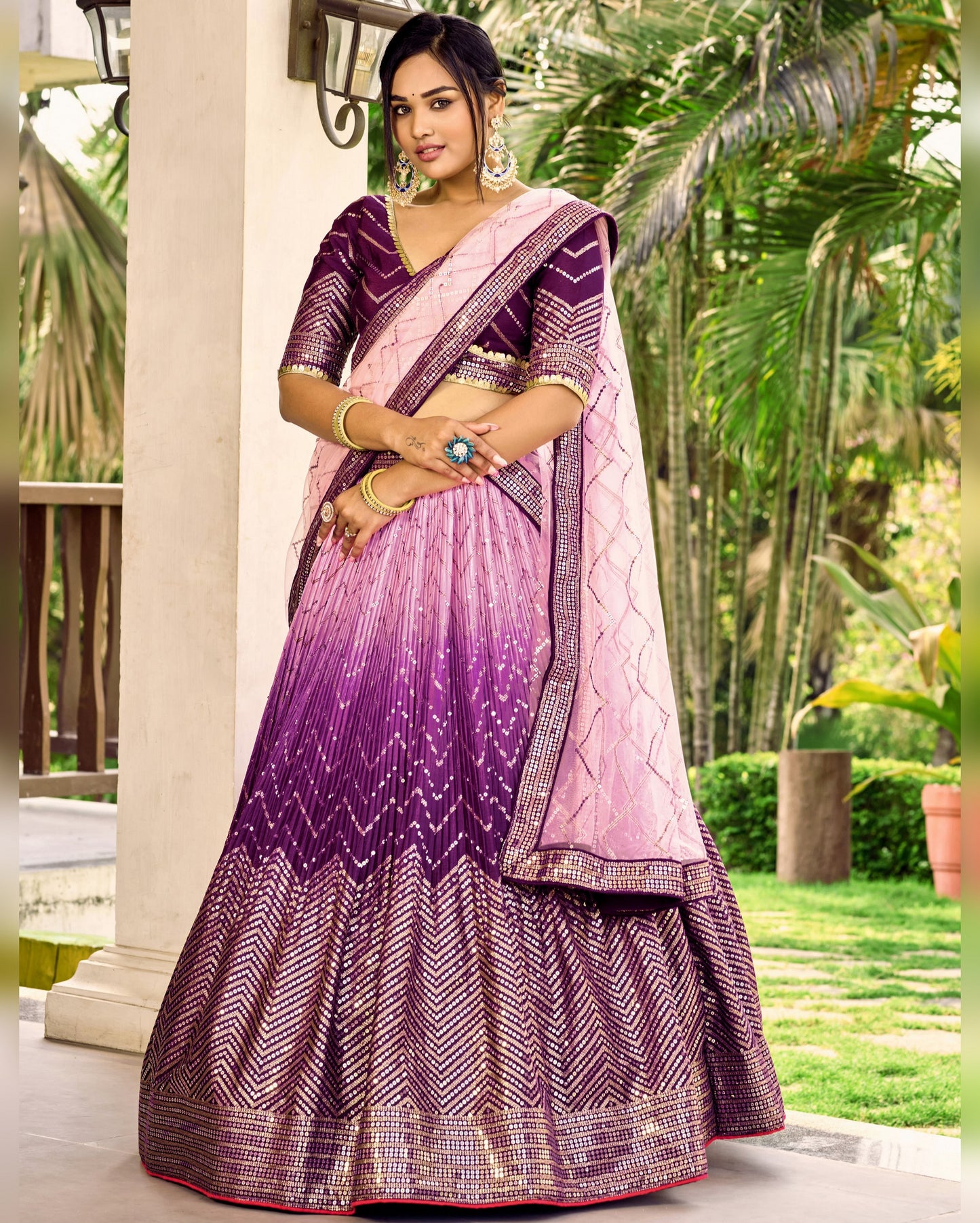 Woman wearing a pink and purple traditional outfit with a garden background