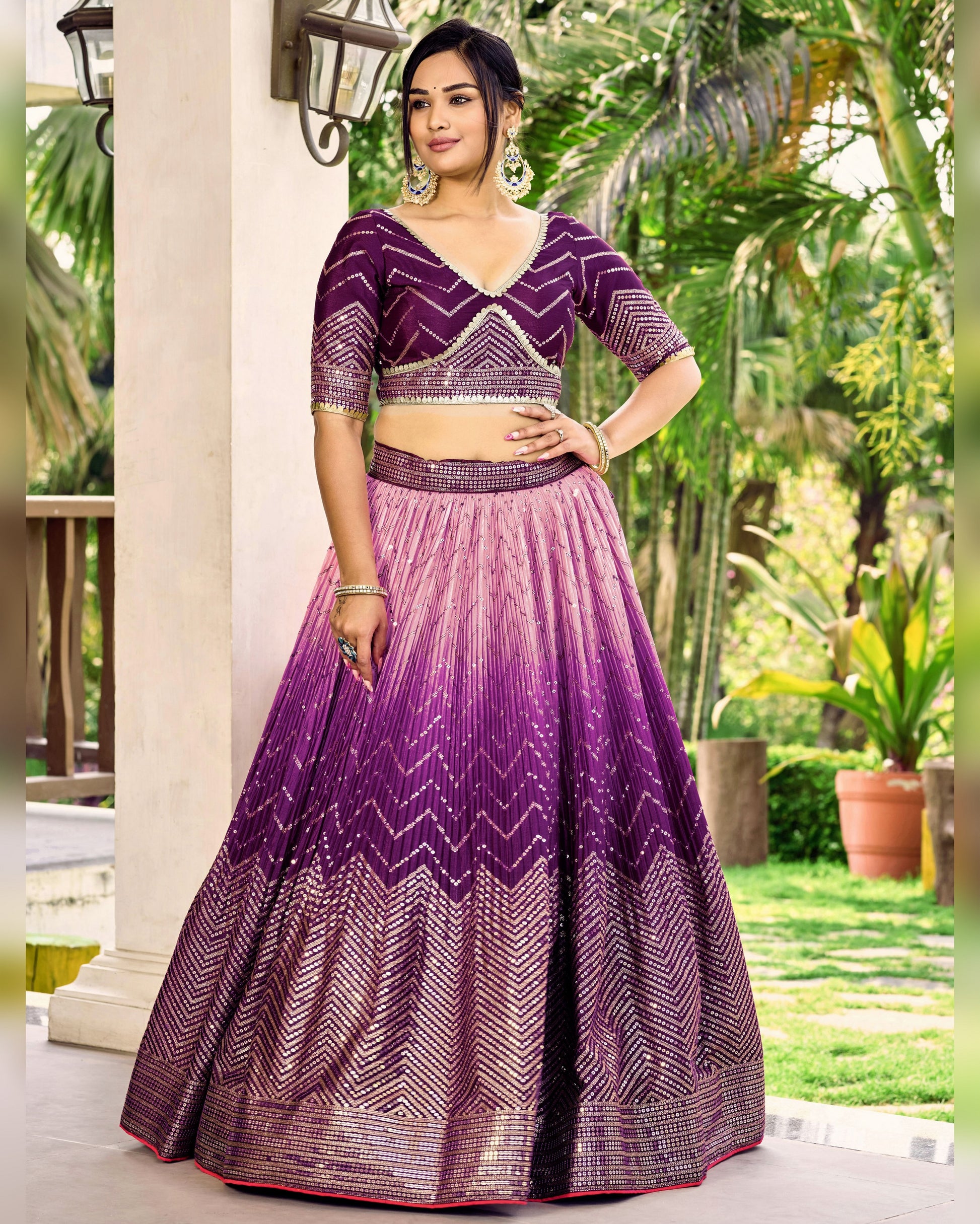 Woman wearing a purple and pink lehenga with a matching blouse in an outdoor setting.