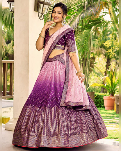 Woman in a pink and purple traditional outfit standing outdoors with greenery in the background