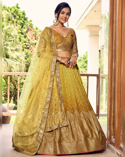 Woman in a yellow and gold traditional outfit standing on a balcony with greenery in the background