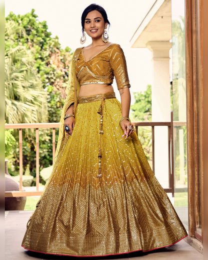 Woman wearing a traditional yellow and gold outfit on a balcony with greenery in the background