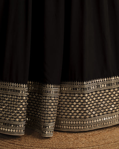 Black fabric with intricate gold embroidery on a textured surface