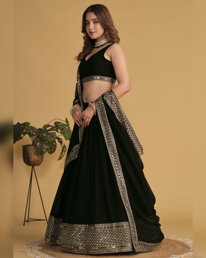 Woman wearing a black embroidered lehenga with a beige background