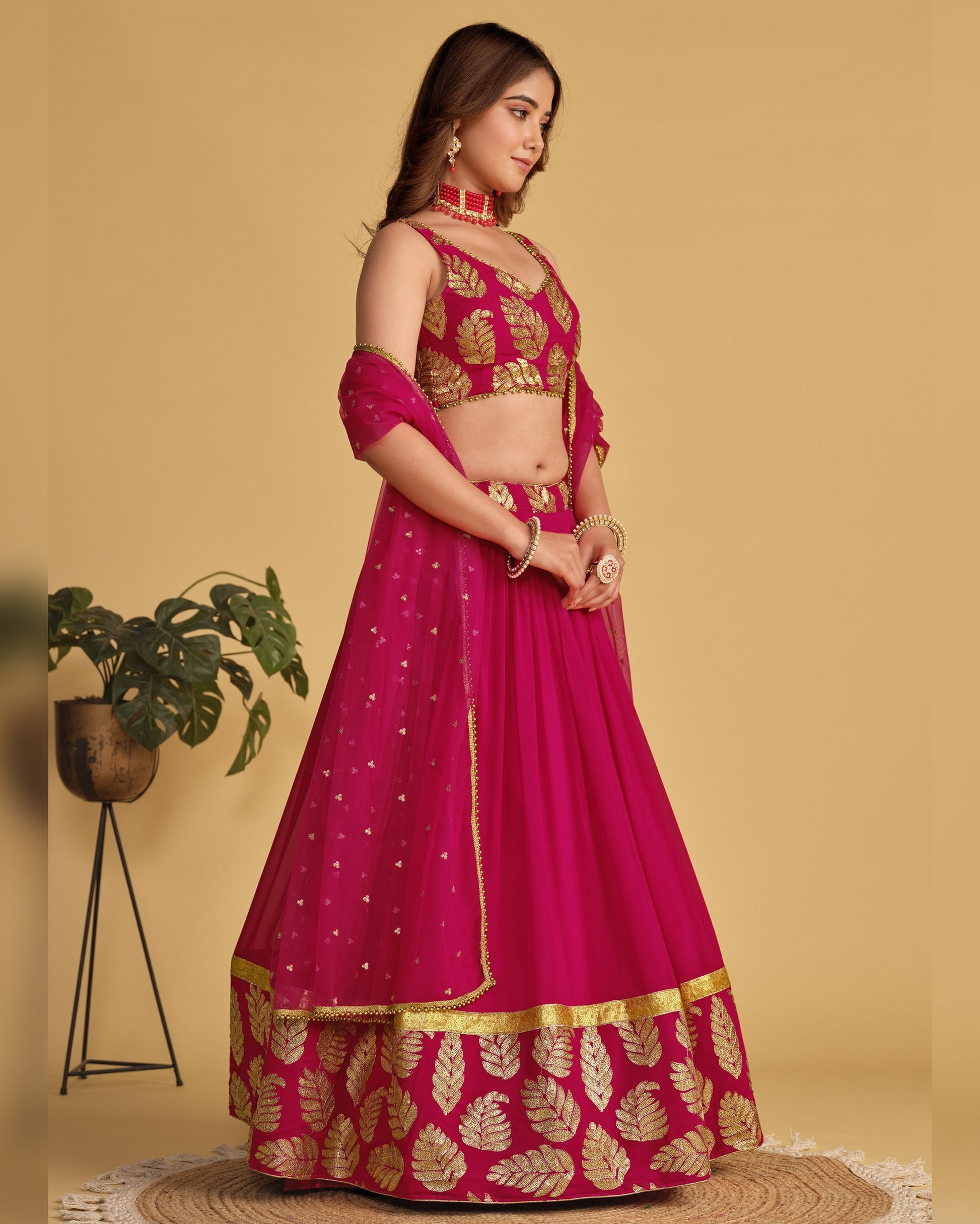 Woman wearing a pink and gold traditional outfit on a beige background