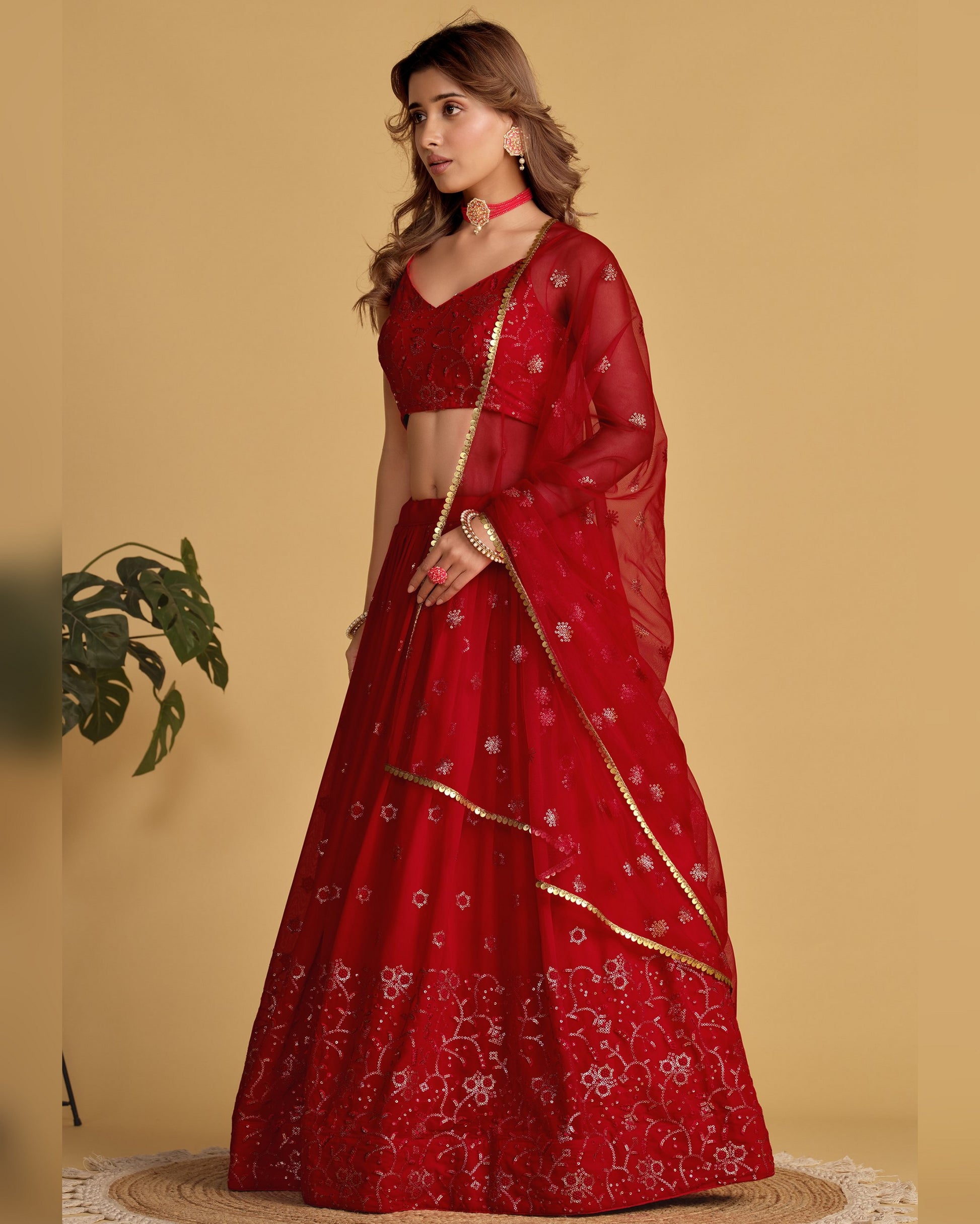 Woman wearing a red embroidered saree with a plain background