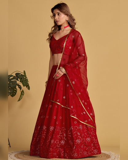 Woman wearing a red embroidered saree with a plain background