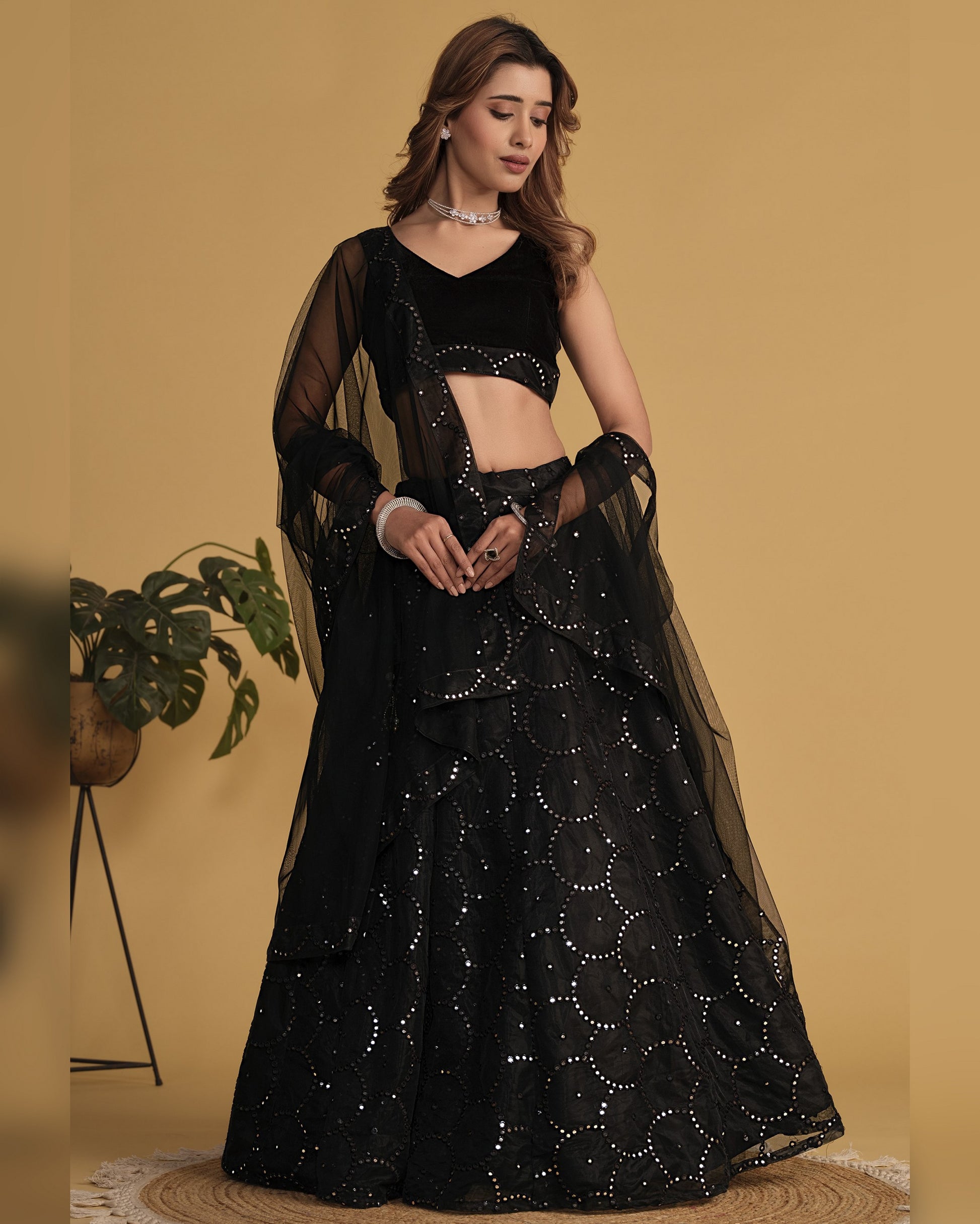 Woman wearing a black traditional outfit with sequin details on a beige background