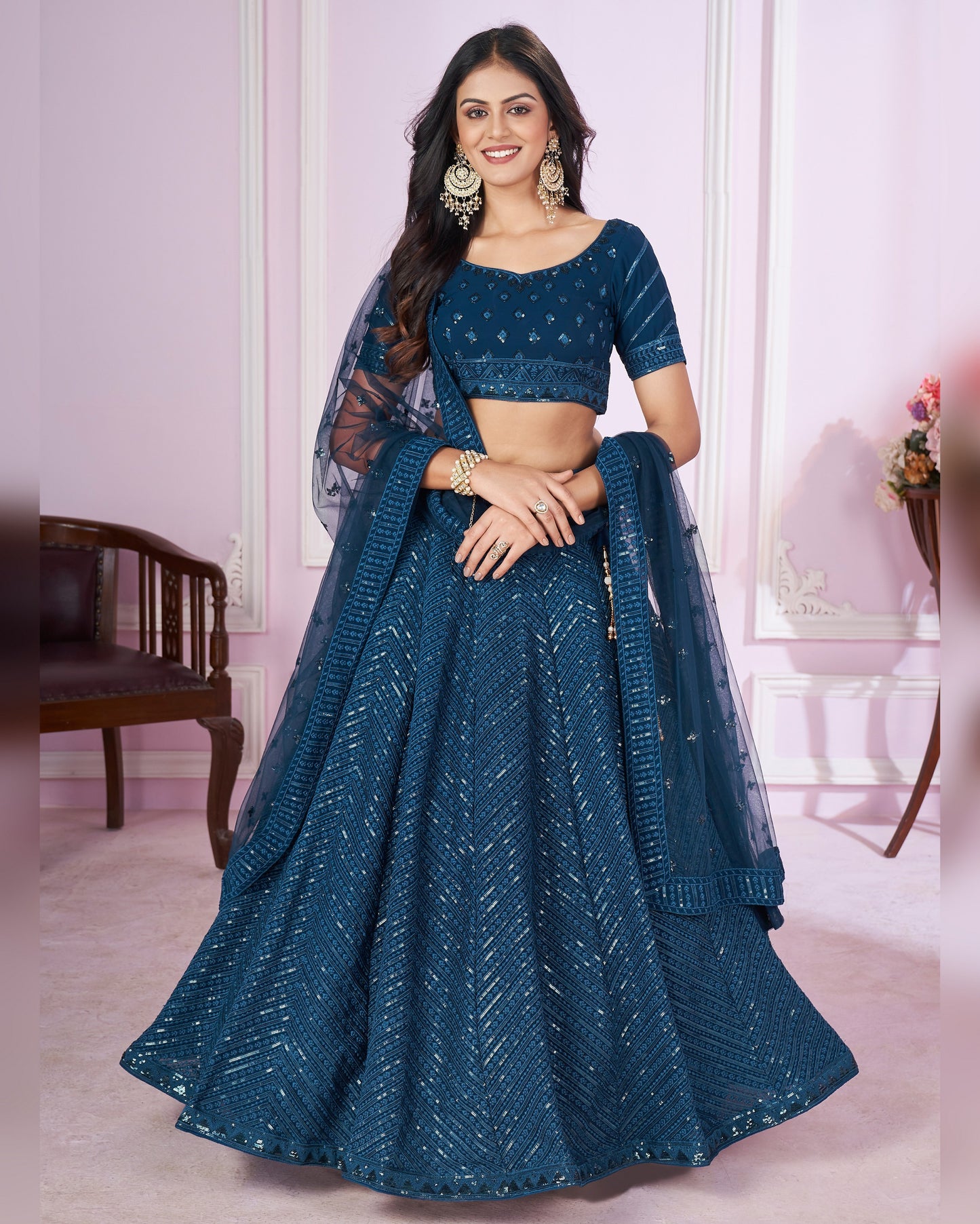 Woman wearing a blue traditional outfit with a matching dupatta in a room setting.
