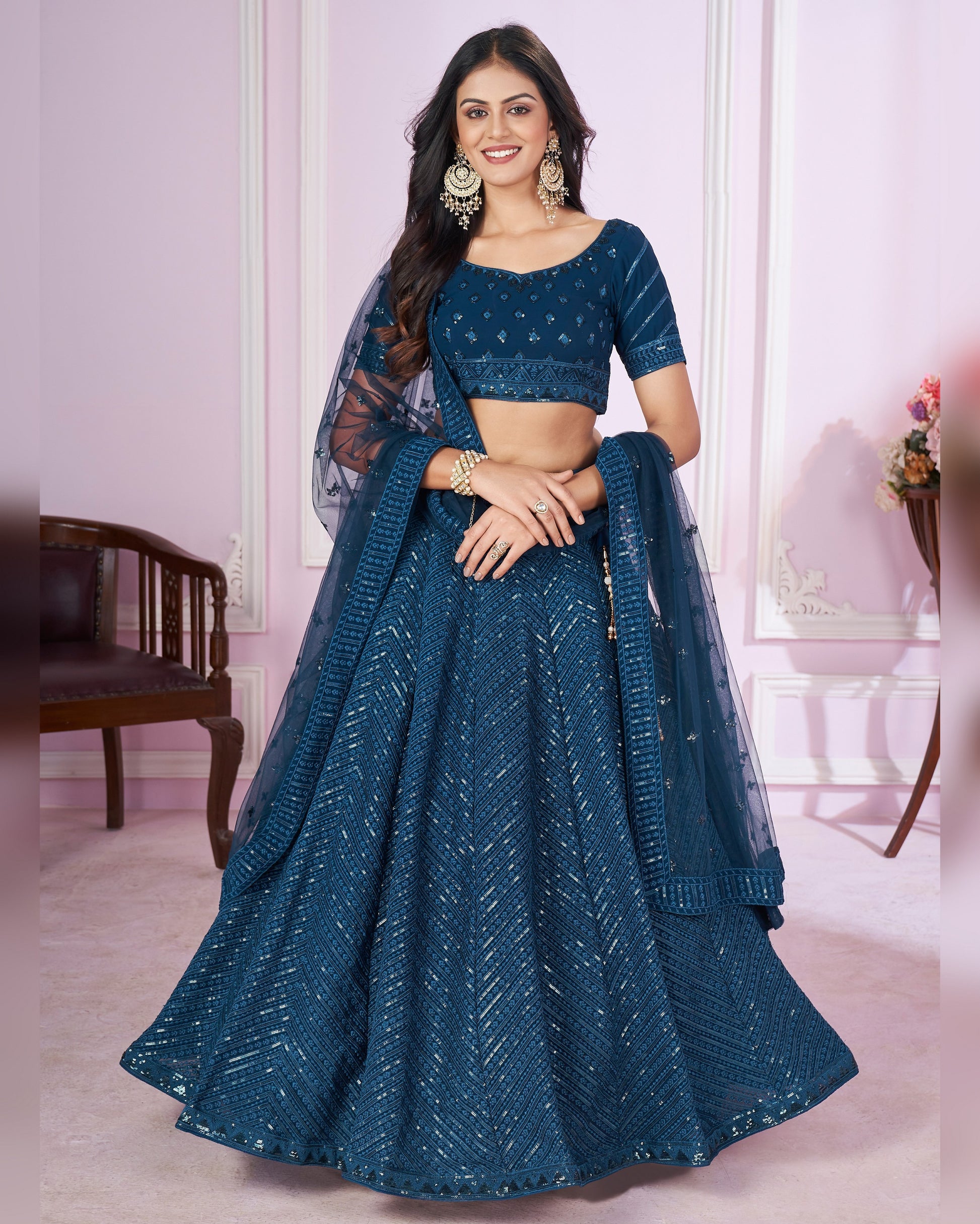 Woman wearing a blue traditional outfit with a matching dupatta in a room setting.