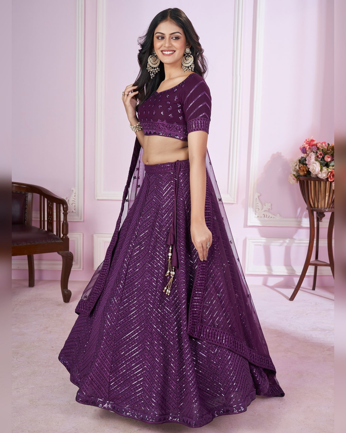 Woman wearing a purple traditional outfit in a decorated room.