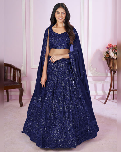 Woman wearing a navy blue embroidered lehenga in an indoor setting