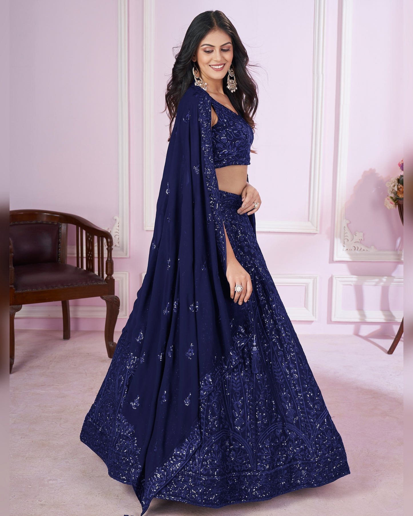 Woman wearing a navy blue embroidered saree in an indoor setting