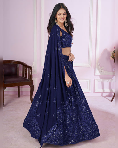 Woman wearing a navy blue embroidered saree in an indoor setting