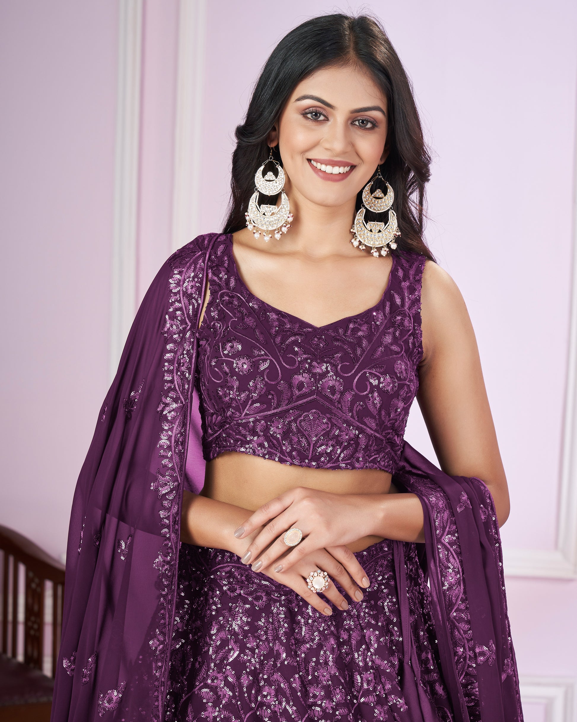 Woman wearing a purple traditional outfit with jewelry against a light background
