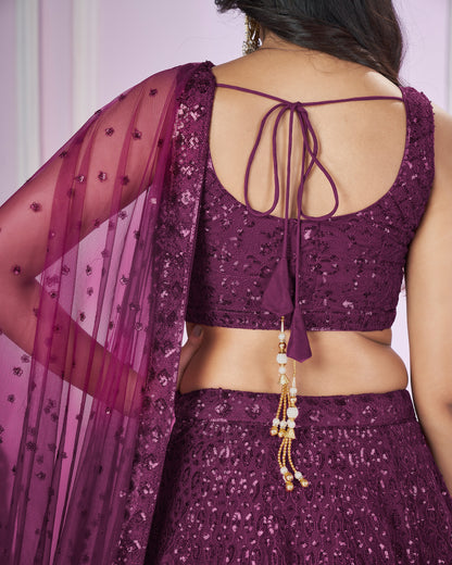 Purple traditional outfit with a sheer dupatta and decorative jewelry on a plain background