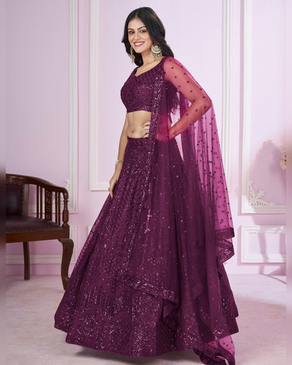 Woman wearing a purple traditional outfit with a matching dupatta in a room.