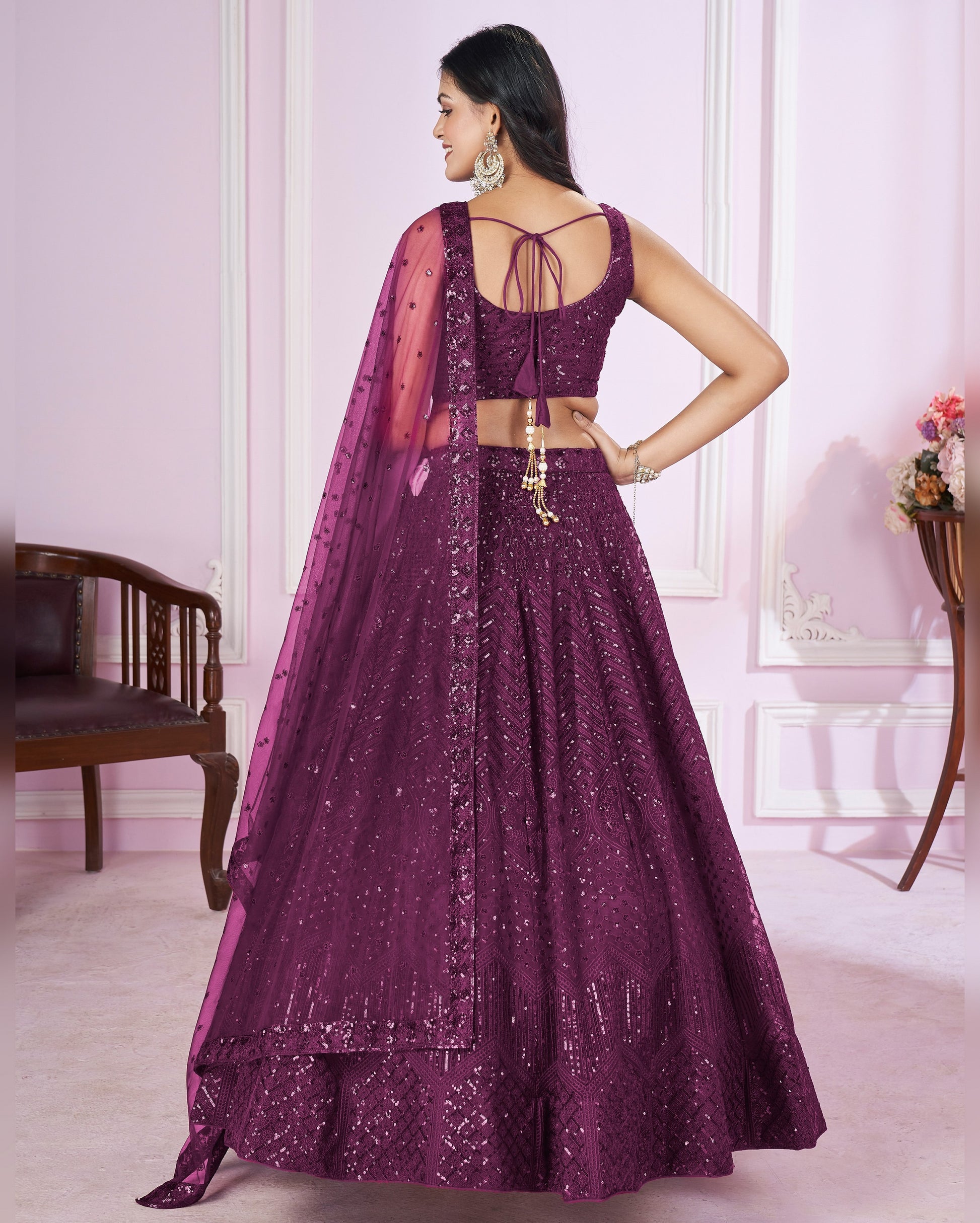 Woman wearing a purple traditional outfit with a matching dupatta in a room.