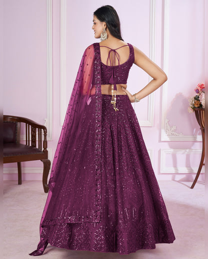 Woman wearing a purple traditional outfit with a matching dupatta in a room.