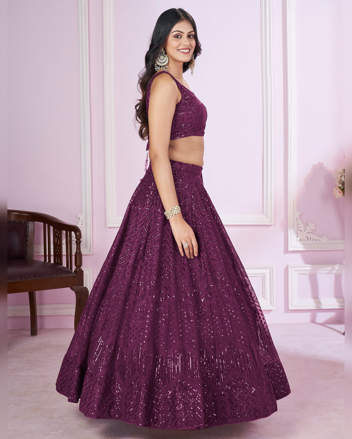 Woman wearing a purple traditional outfit in a room with pink walls.
