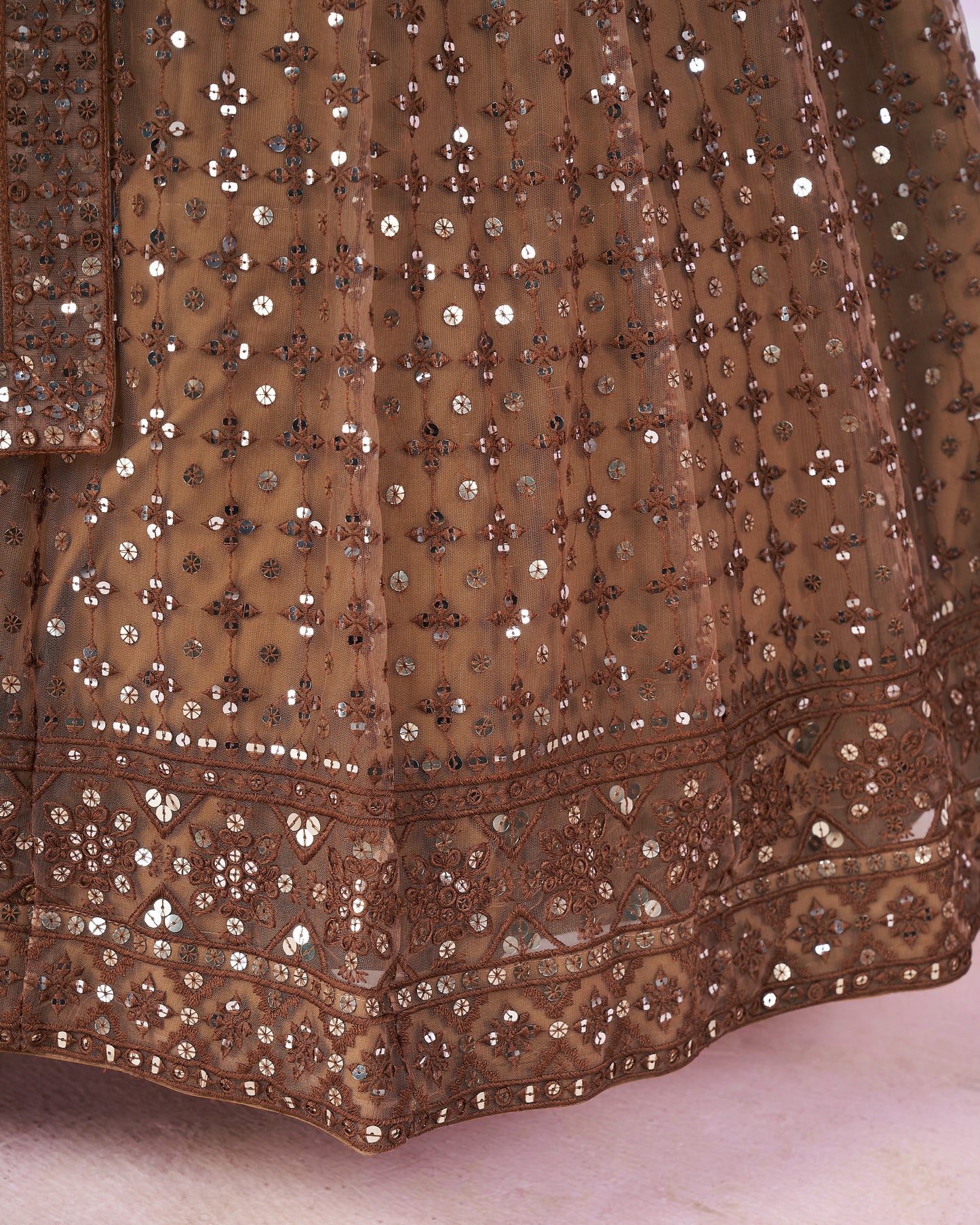 Close-up of a brown embroidered fabric with intricate patterns on a light background
