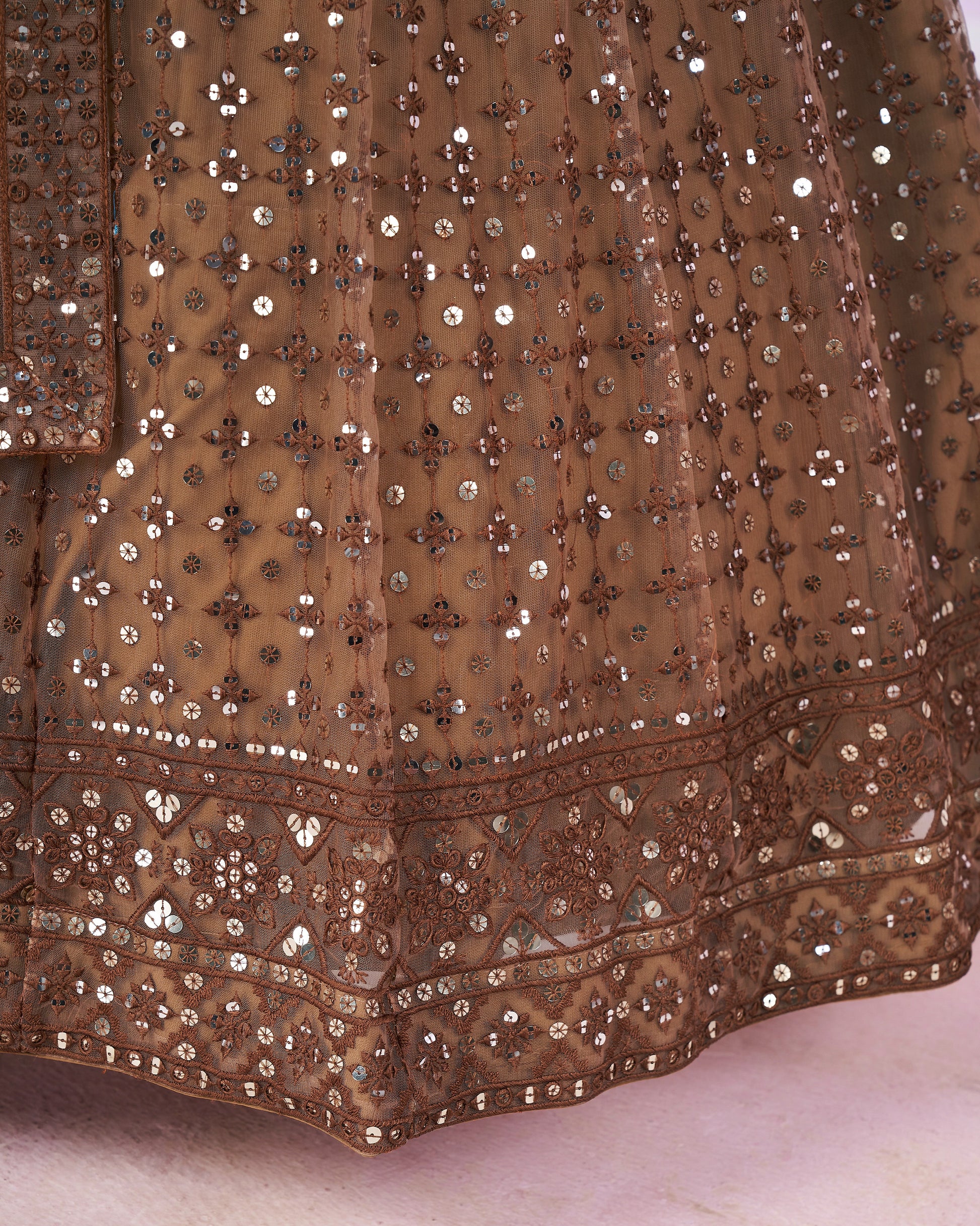 Close-up of a brown embroidered fabric with intricate patterns on a light background