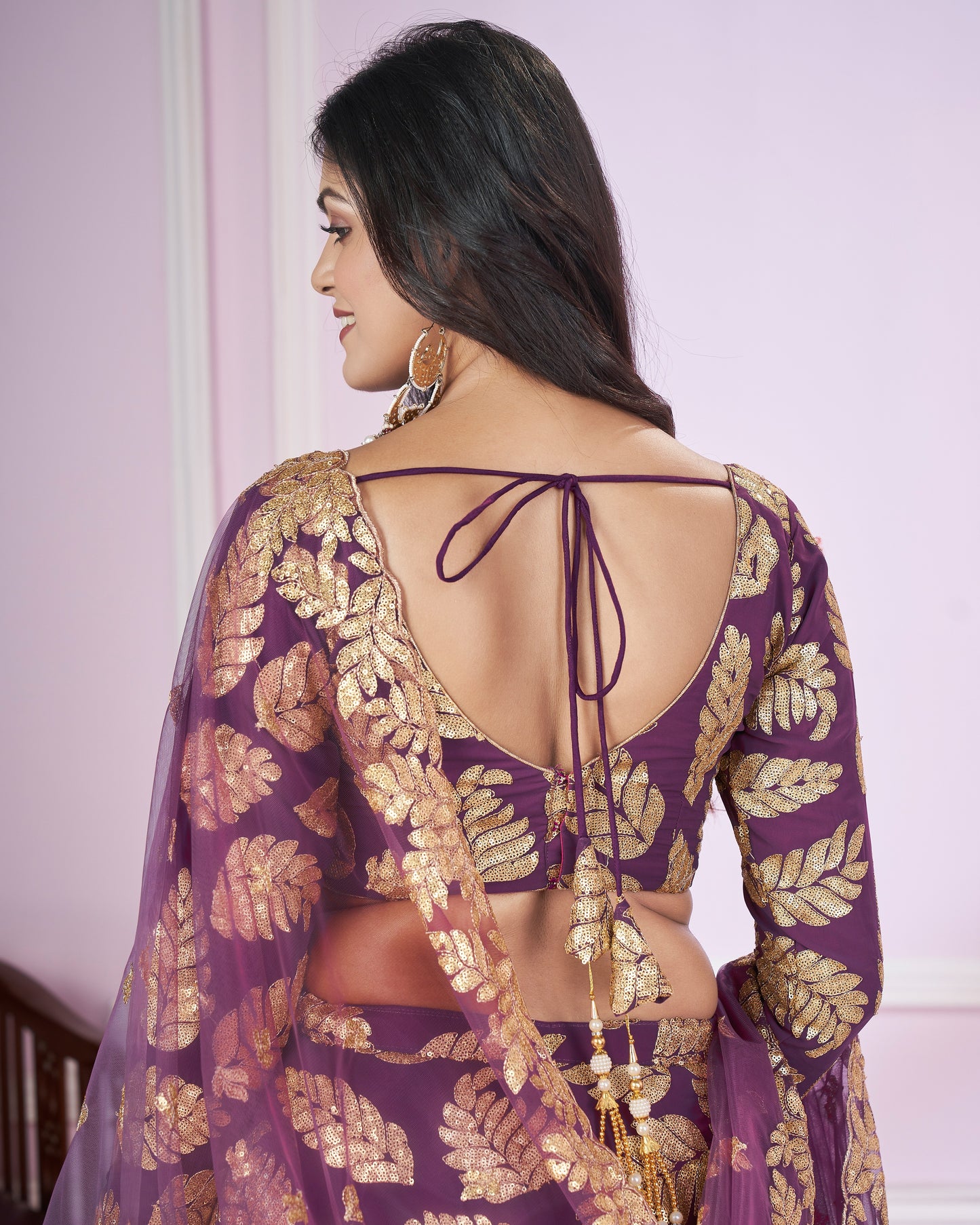 Woman wearing a purple and gold traditional outfit with a backless design.