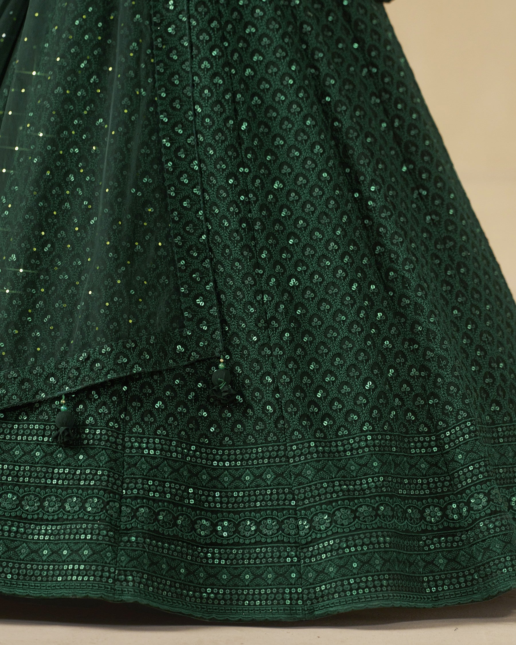 Close-up of a green embroidered fabric with a beige background