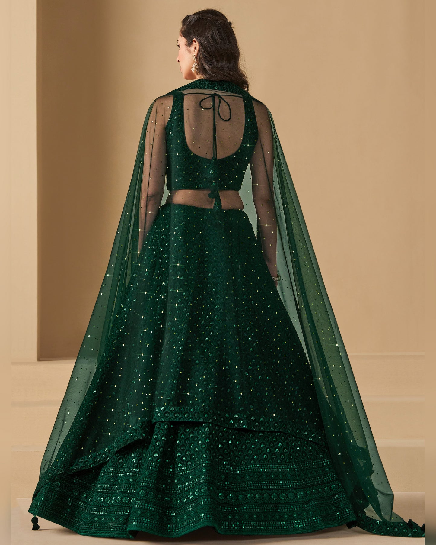 Green traditional outfit with a sheer cape on a beige background