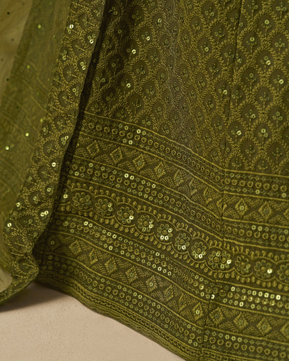 Close-up of a green embroidered fabric with sequins on a beige background