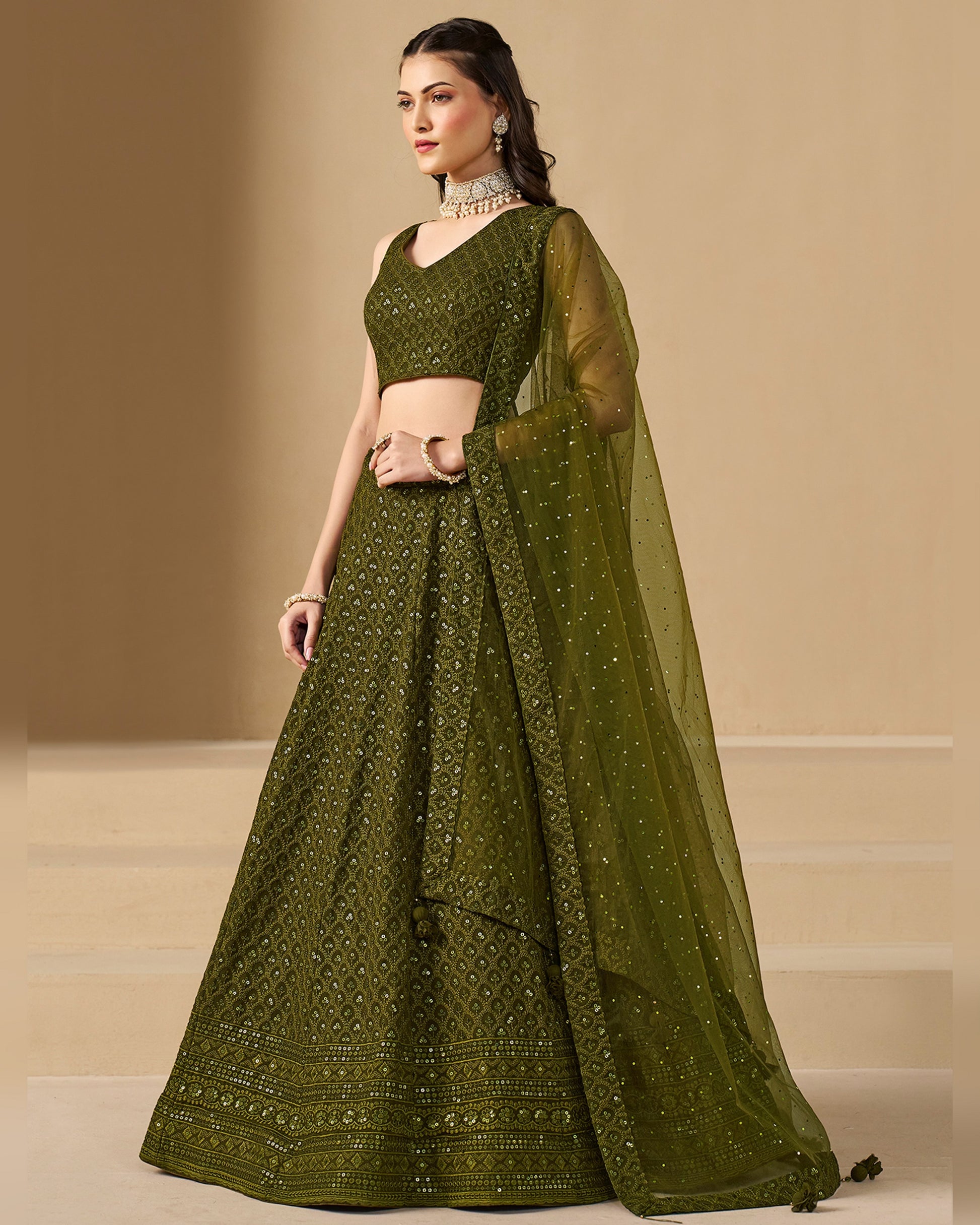 Woman wearing a green traditional outfit with a beige background