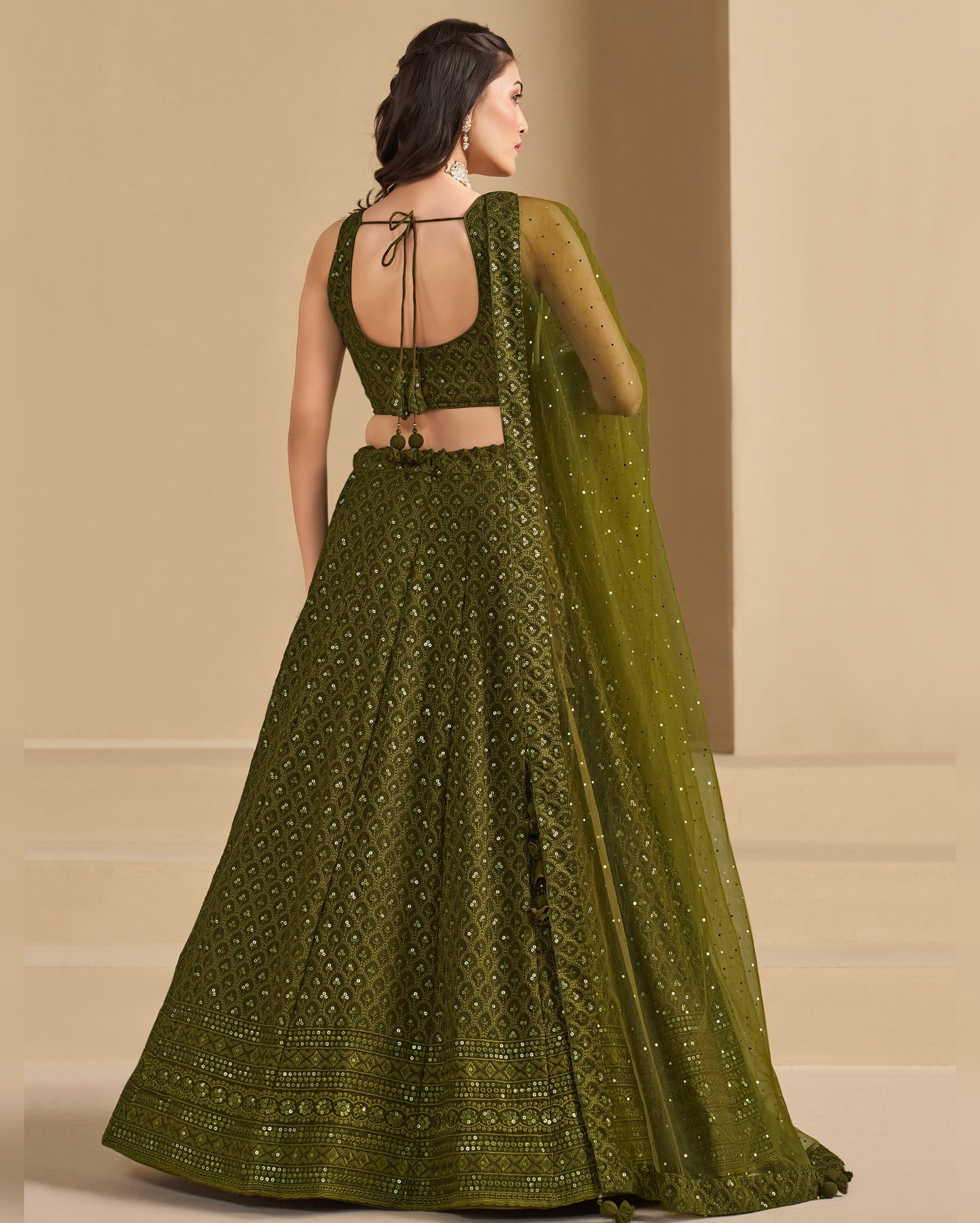 Woman wearing a green embroidered traditional outfit with a beige background