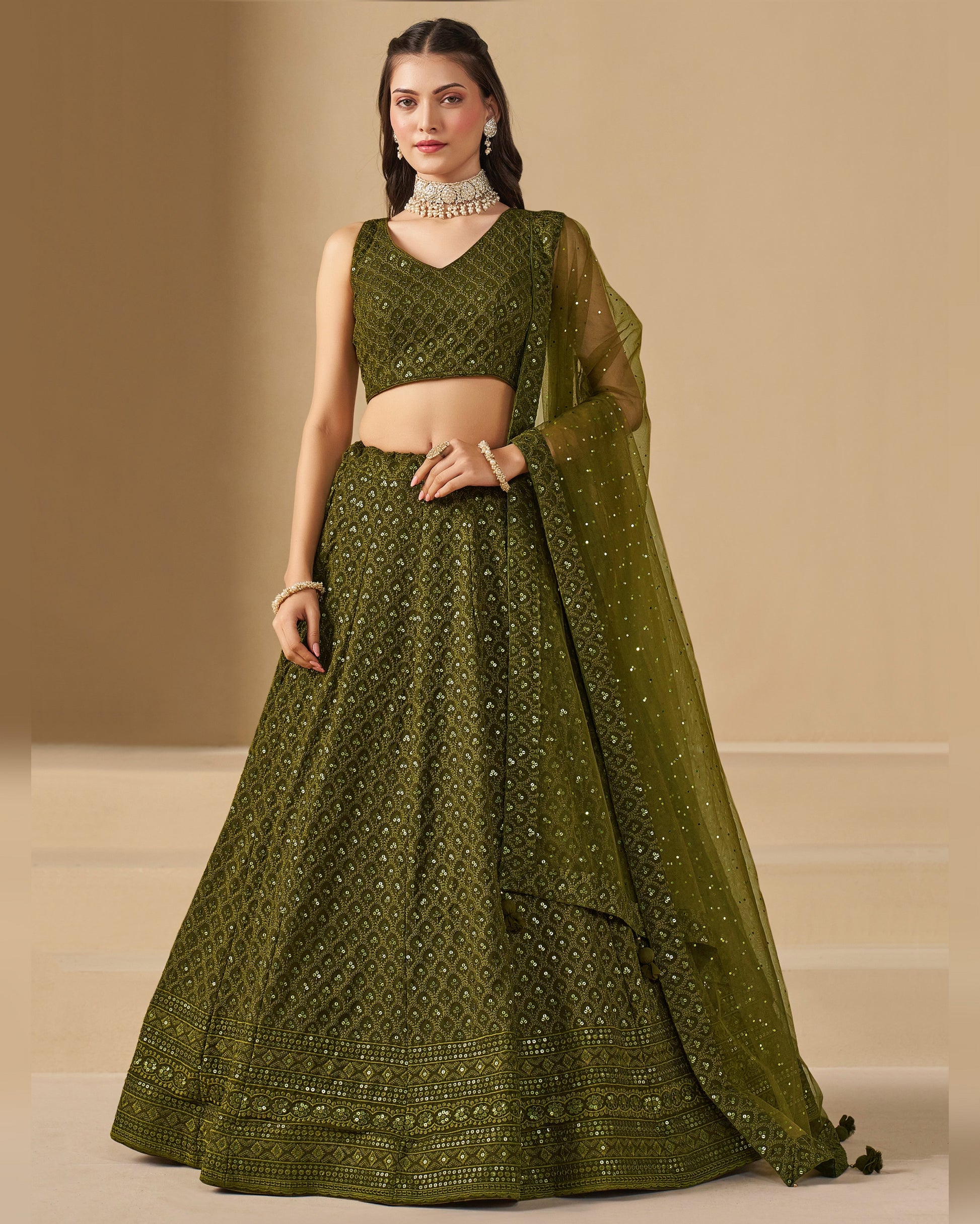 Woman wearing a green traditional outfit with a beige background