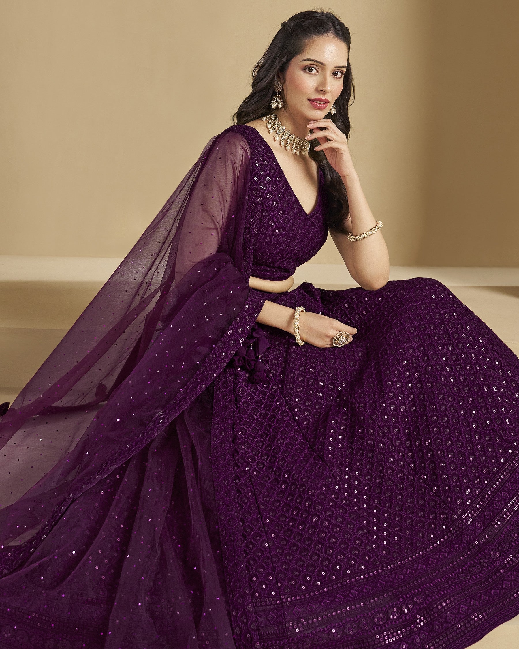 Woman wearing a purple saree with a beige background