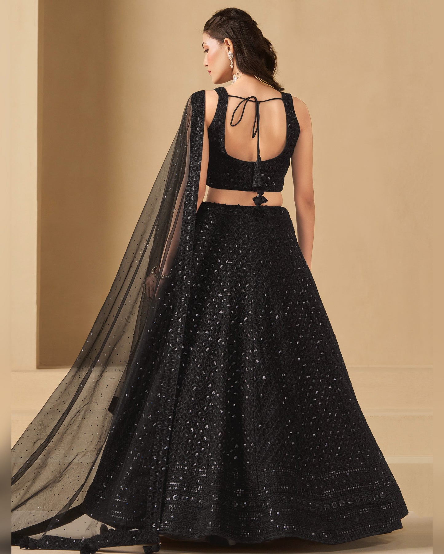 Black embroidered lehenga with sheer dupatta on a beige background